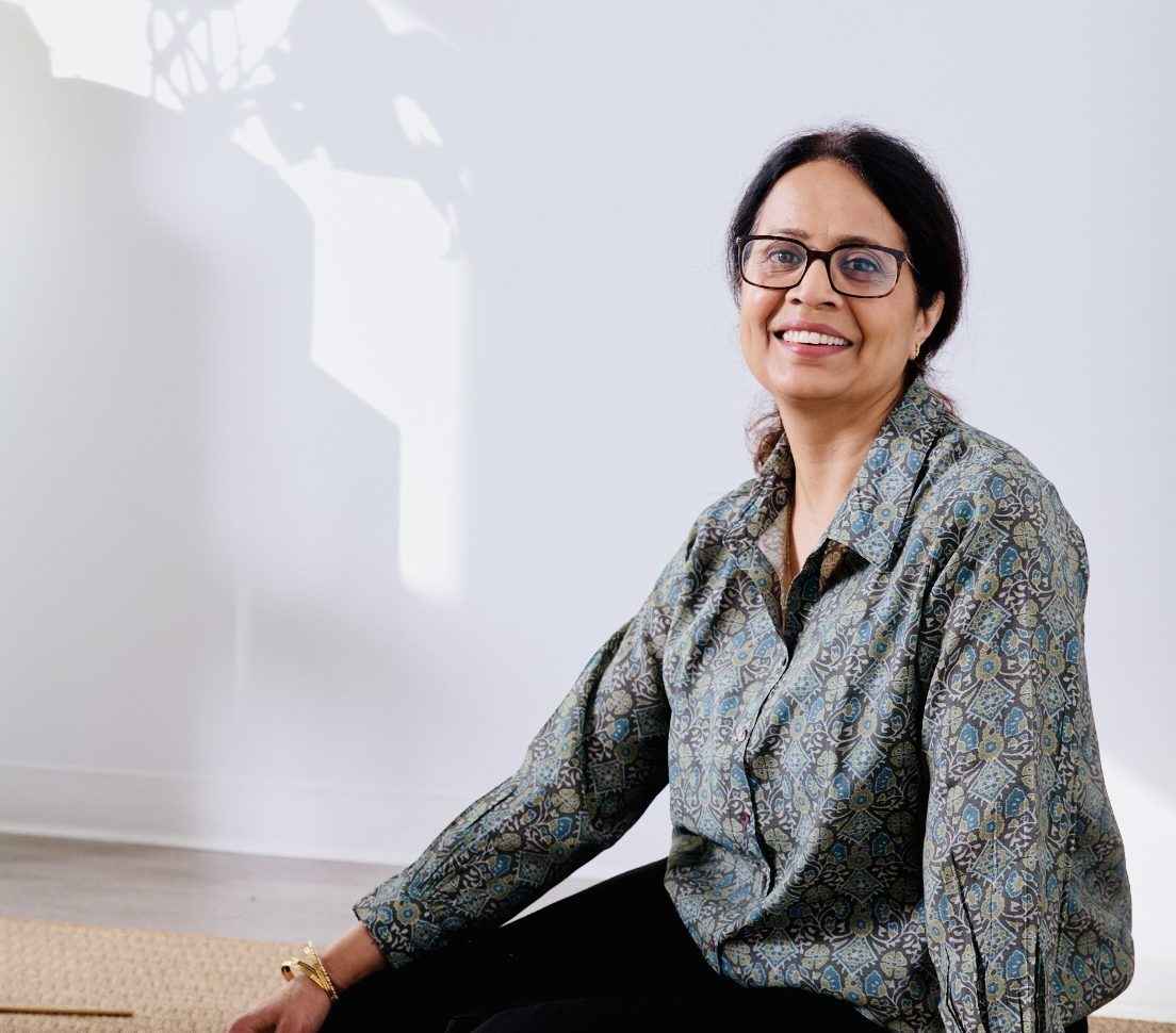 A woman smiling, sitting on the ground.