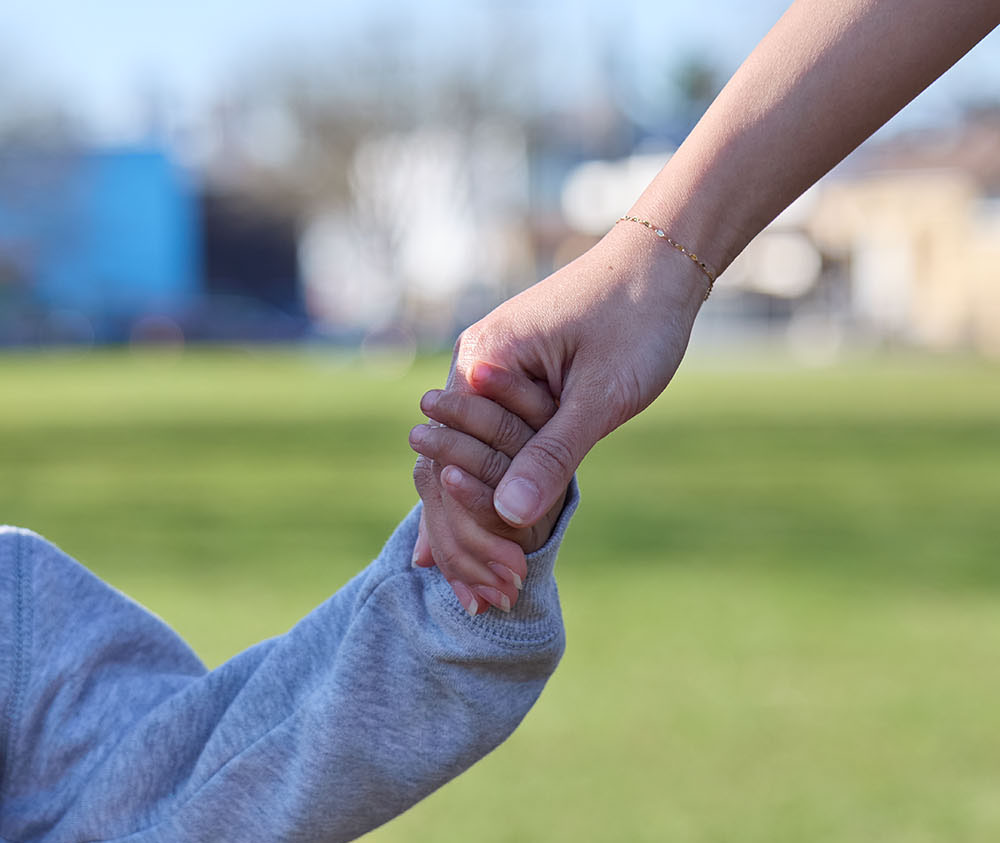 A zoomed in picture of a mom and son holding hands